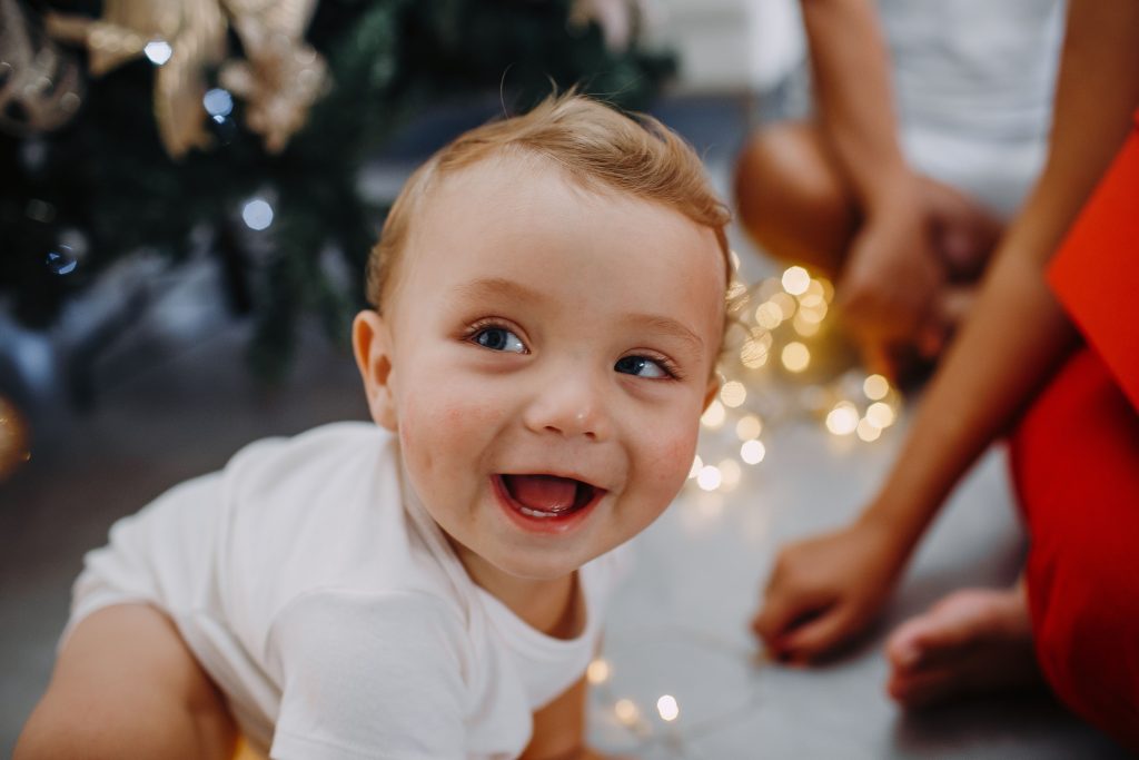 A happy baby enjoying Christmas lights and holiday atmosphere indoors.