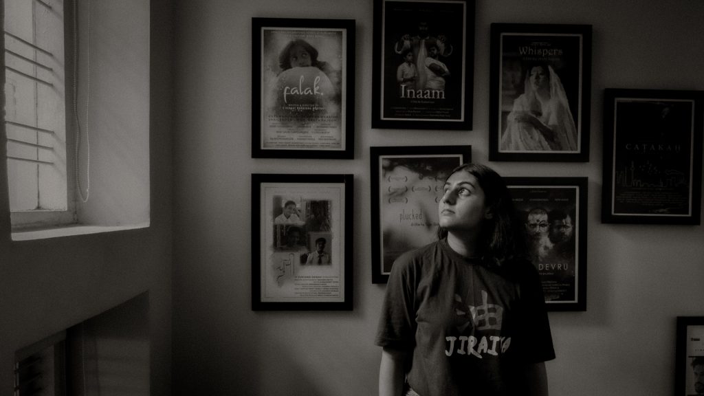 Black and white photo of a woman in an art gallery with framed portraits on the wall.