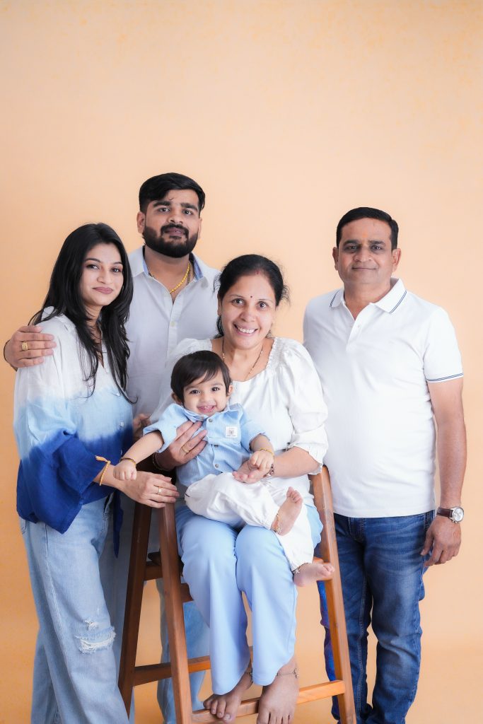 A joyful family of five posing in stylish casual wear against a peach backdrop.